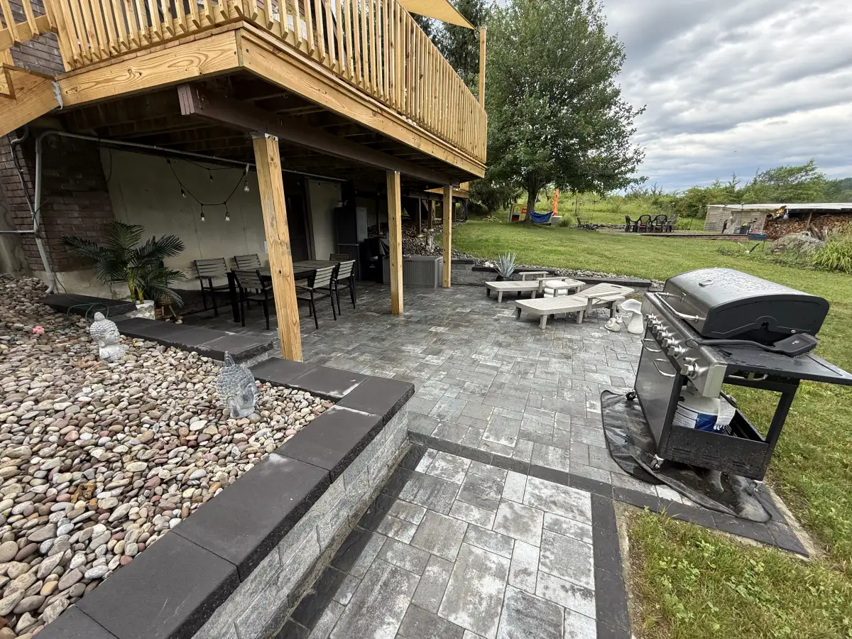 Finished paver patio with sitting and grilling areas beside a raised deck